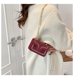 Detail of red suede mini bag featuring white wave stitching and gold chain strap