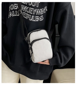 Detailed view of cream checkered crossbody bag with double zippers and nylon shoulder strap