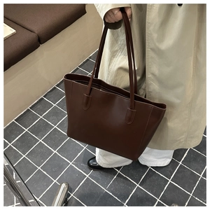 Close-up of a dark brown luxury tote bag with premium leather texture and long straps
