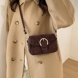 Retro dark brown suede shoulder bag with gold metal buckle shown on a stylish wool coat