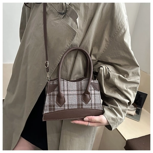 Détail d'un sac seau à carreaux avec garniture et bandoulière en similicuir brun