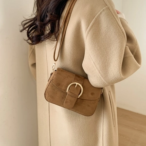 Detail of vintage brown frosted crossbody bag featuring large gold round buckle closure