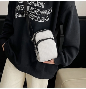 White checkered crossbody bag with adjustable strap worn over a black hoodie for contrast