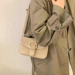 Chic beige suede crossbody bag with gold horseshoe buckle worn with olive coat