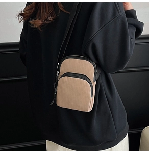 Detail of khaki canvas crossbody bag showing dual zipper compartments and nylon strap