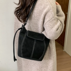 Sac à bandoulière minimaliste en daim noir avec surpiqûres contrastées sur un mannequin