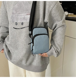 Detail of light blue canvas crossbody bag showing compact size and adjustable strap