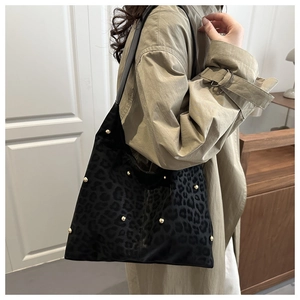 Dettaglio borsa leopardata con borchie dorate indossata da modella in trench