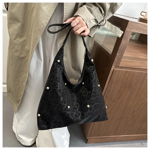 Detail of suede black hobo bag with leopard print and golden rivet decorations
