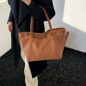 Brown suede tote bag with slim handles worn with a coat for a stylish winter look
