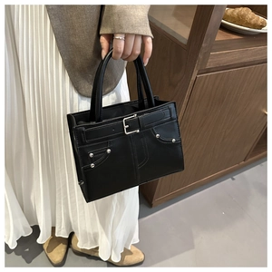 Détail d'un sac à main vintage noir avec boucle métallique et rivets décoratifs