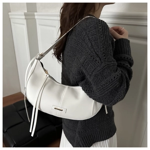 Detail of white hobo shoulder bag with gold hardware and long tassels decoration
