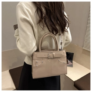 Détail d'un sac à main beige minimaliste avec boucle argentée et poche latérale sur un mannequin
