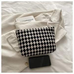 Detail of black and white checkered knit makeup bag on textured corduroy fabric