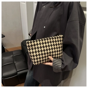 Close-up of vintage houndstooth knit toiletry bag with metal zipper being held by a hand
