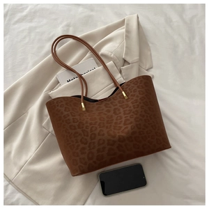 Macro shot of stylish leopard print tote bag with brown straps and gold metal hardware