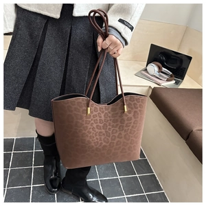 Close-up of leopard print tote bag with brown leather handles and gold metal hardware