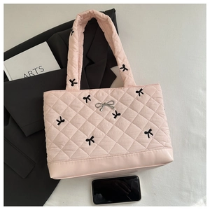 Detailed view of pink quilted tote bag with black bow embroidery and silver charm