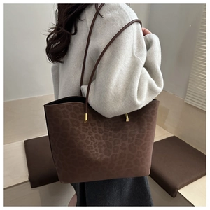Detail of leopard print suede tote bag featuring sleek golden cylindrical metal buckles