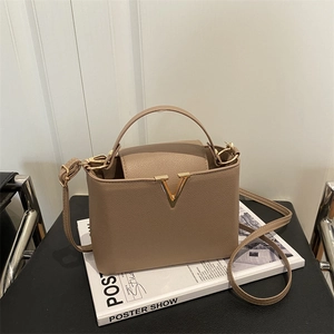 Minimalist khaki leather bucket bag with V-shaped gold buckle and thin shoulder strap