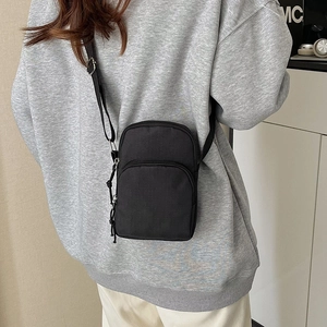 Minimalist black nylon crossbody bag with dual zippers and adjustable shoulder strap