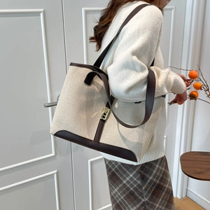 Grand sac cabas en toile beige avec finitions en cuir marron et boucle dorée sur mannequin