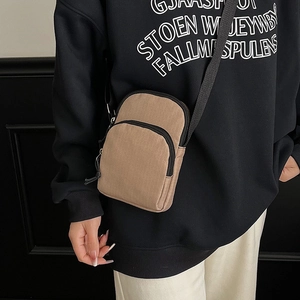 Minimalist khaki crossbody bag with adjustable black strap shown on a female model