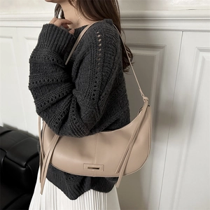 Sac à bandoulière minimaliste beige en forme de croissant avec détails en métal et glands
