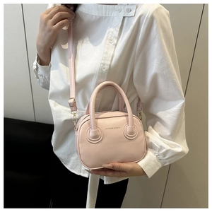 Detail of light pink mini pillow crossbody bag with golden hardware and adjustable strap