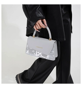 Gros plan d'un sac à main gris clair avec finitions dorées et motifs graffiti blancs