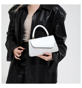 Détail du sac à main blanc en cuir verni avec panneau structuré et finitions dorées