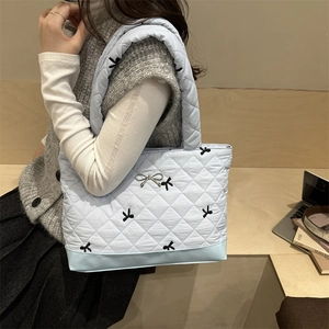 Borsa tote trapuntata celeste con ricami a fiocco neri e decorazione in metallo argento