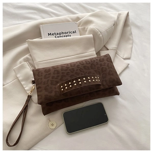 Vue détaillée d'une pochette léopard à rivets dorés sur un blazer beige chic