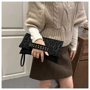 Détail du sac en daim léopard avec poignée cloutée dorée dans un décor décontracté