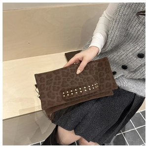 Détail d'un sac à main léopard avec clous dorés sur la sangle et texture en daim