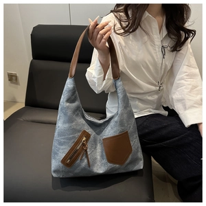 Detail of grey-blue canvas tote bag with brown leather pockets shown in a lifestyle scene
