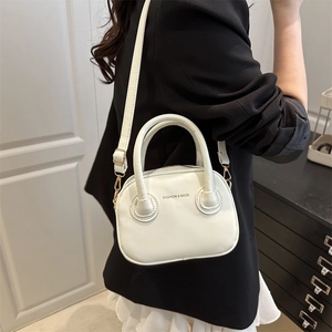 Mini sac Boston blanc avec détails dorés et bandoulière porté par un mannequin