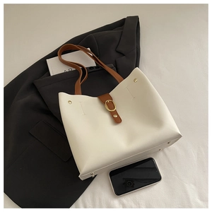 Detail of cream tote bag with brown straps and golden buckle on a black blazer