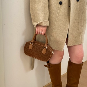 Detailed view of leopard print handbag paired with beige coat and brown boots