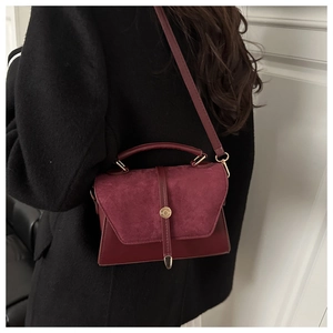 Détail du sac bandoulière bordeaux en cuir givré montrant la boucle métal et texture rétro