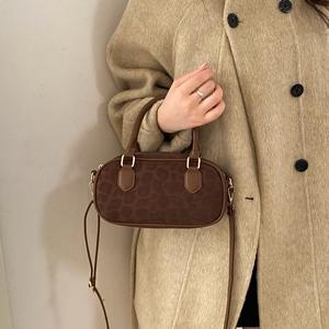 Dark brown oval animal pattern handbag with detachable shoulder strap worn by model