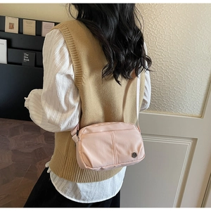 Détail du sac bandoulière en nylon rose clair avec coutures et sangle large
