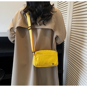 Vue arrière d'un mannequin portant un sac à bandoulière en nylon jaune vif et sangle large