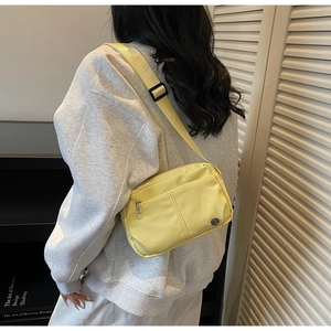 Vue arrière du modèle portant un petit sac bandoulière en nylon jaune avec sangle