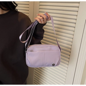 Détail du sac bandoulière en nylon lilas avec logo en métal et bandoulière réglable