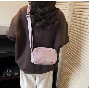 Détail du sac bandoulière en nylon lavande montrant la sangle et le logo en métal
