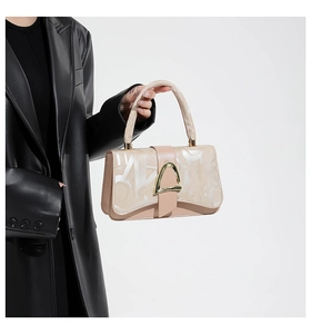 Detail of elegant beige crossbody bag with gold triangle clasp and leather texture