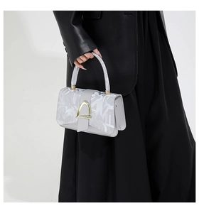 Close-up of light grey handbag with horse-bit gold buckle and stylish letter patterns