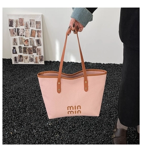 Detail of pink canvas tote bag featuring brown leather straps and min min embossed logo