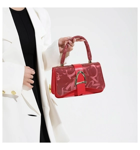 Detail of red leather handbag with abstract embossed patterns and a gold triangular clasp